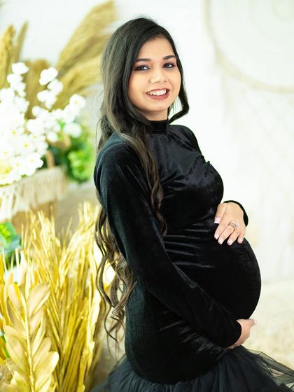 A sweet and simple portrait of a mom-to-be in a black velvet dress. The golden-hued props in the background add a touch of warmth.