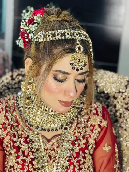 This is my signature bridal look. For this Nikkah bride, I created a soft, smoky eye with a nude lip, paired with a floral bun. The matha patti and heavy jewelry complete this elegant and timeless style.
