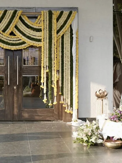 A traditional welcome at the entrance, with marigold garlands, lotus-themed decor, and cow figurines symbolizing prosperity and auspicious beginnings.