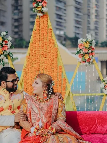 A sweet portrait of the couple seated together at their poolside Haldi ceremony. The colorful decor and their happy interaction make for a beautiful memory.
