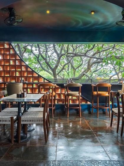 The final look of the transformed dining space, featuring custom furniture, unique planters, and a cohesive design that blends artistic murals with natural elements like the terracotta brick screen.