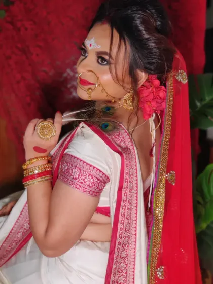 A side view showing the elegant bun, red flower adornments, and the intricate design of her earrings.