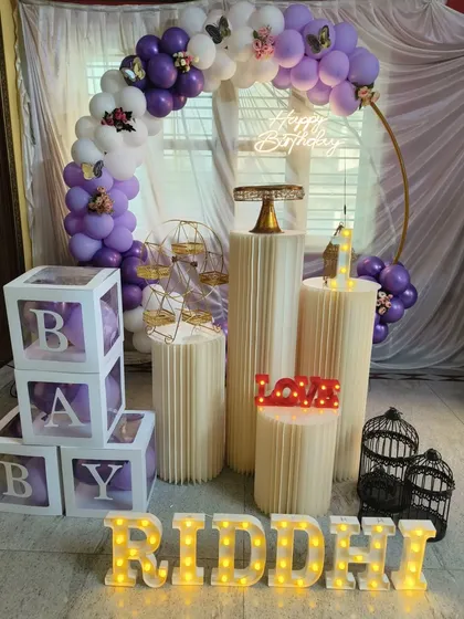 A closer look at the purple butterfly-themed decor, showing the arrangement of props like the miniature ferris wheel, birdcages, and light-up name.