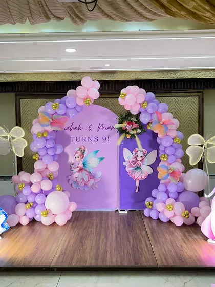 A whimsical fairy and butterfly themed birthday stage. This setup features two purple backdrops, pastel balloon arches, and large, illuminated butterfly cutouts alongside princess characters like Cinderella and Aurora.