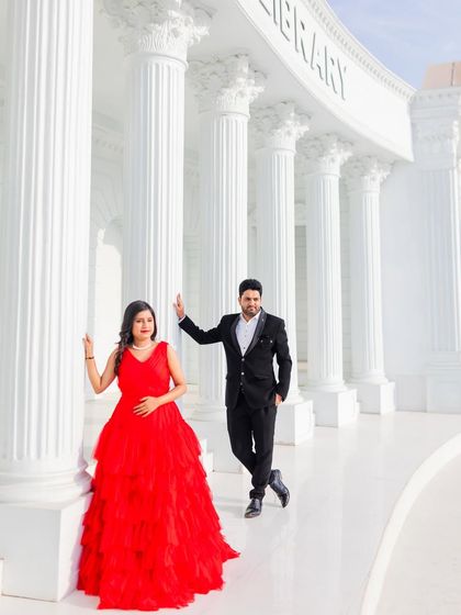 A stylish portrait at a set replicating the Asiatic Library. The woman's red dress provides a striking contrast against the white pillars.
