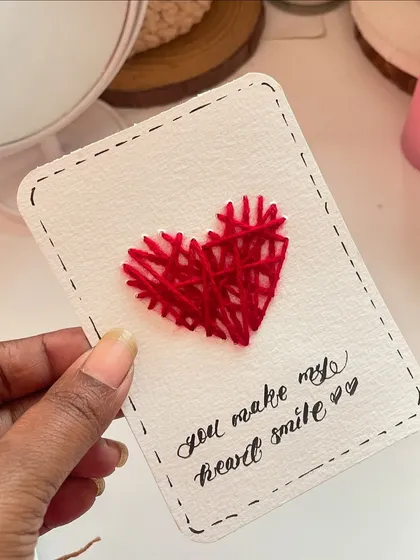 A close-up of the hand-stitched heart card. The texture of the thread on the paper makes it so much more special than a printed card.