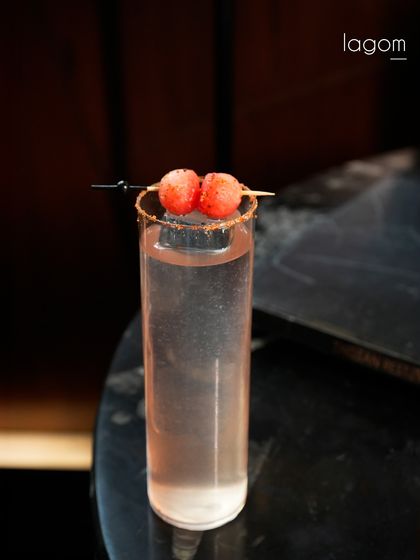 The Lagom cocktail is a testament to balance. This highball features two small watermelon balls on a skewer, hinting at the crisp and refreshing flavors within. It is a perfectly composed drink for any occasion.
