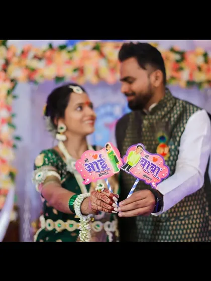 The happy couple holds up 'Aai' (Mom) and 'Baba' (Dad) props, a popular and fun addition to baby shower photography that celebrates their new roles.