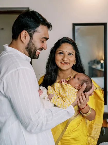 A bright and happy family portrait during a naming ceremony, with the newborn looking alert and engaged with her parents.