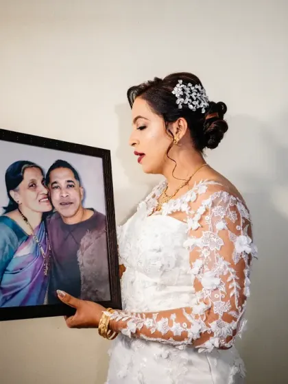 The bride holds a portrait of her beloved parents who are no longer with her. It's a privilege to capture these deeply personal moments of remembrance and love.