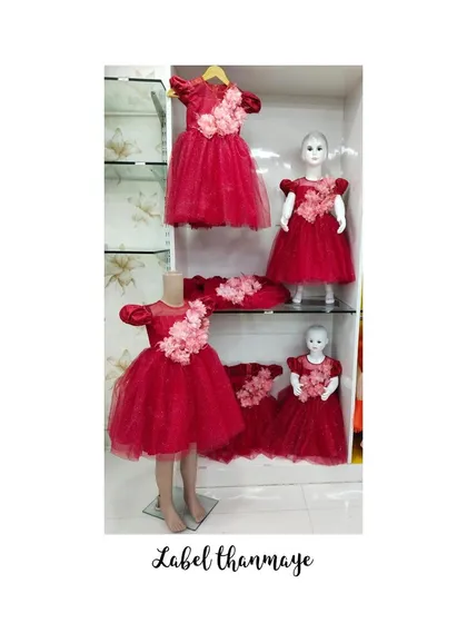 A display of elegant red party frocks with delicate puff sleeves and pink floral appliqué, showing the range of formal designs I can create for groups.