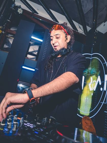 A low-angle shot showing me twisting the knobs on the mixer, crafting the sound under cool blue lighting with my logo in the background.