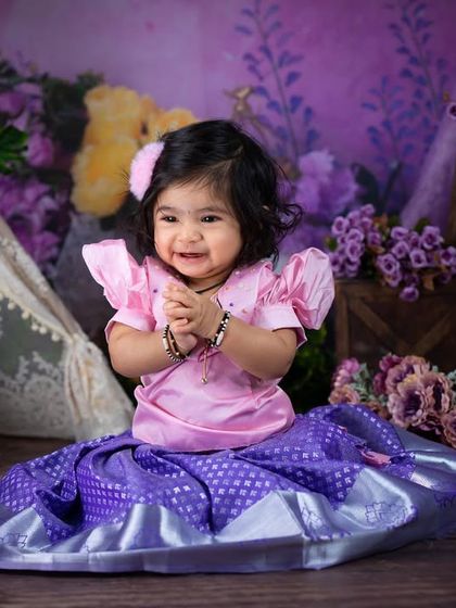 A touch of tradition with this beautiful South Indian "pattu pavadai" outfit. The purple and pink colors look stunning against the floral backdrop.