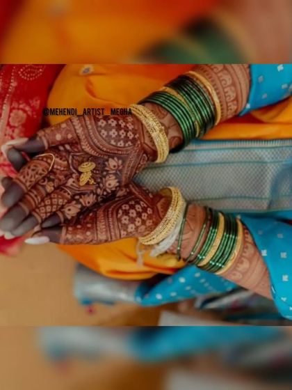 A shot capturing the beauty of the final henna stain during a wedding ritual. The dark color looks stunning with the bride's colorful bangles and sari.