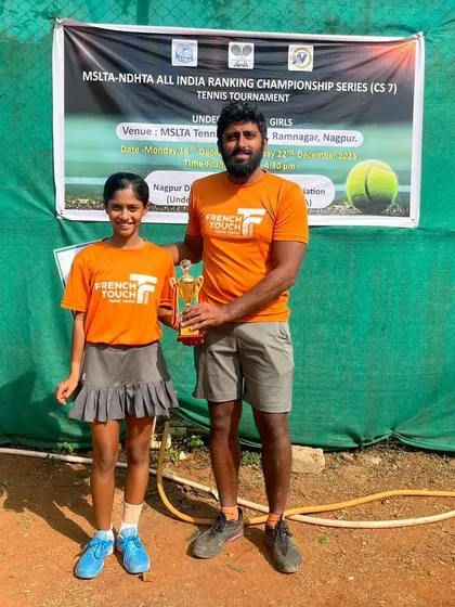 A coach and player celebrate a singles victory. Eshal Pathan with her coach and trophy after winning the All India Tennis Association Championship Series U16 tournament.