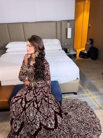 A full-length shot of the bride in her deep maroon Walima gown. The look is regal and elegant, perfect for a grand reception.