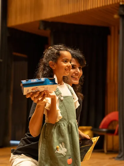 A happy moment of recognition as a student receives a gift after the show. We believe in celebrating every child's contribution.