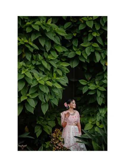 The bride-to-be is framed by a wall of vibrant green leaves, making her pastel lehenga pop. This portrait showcases how I use natural elements to create stunning, colorful compositions.