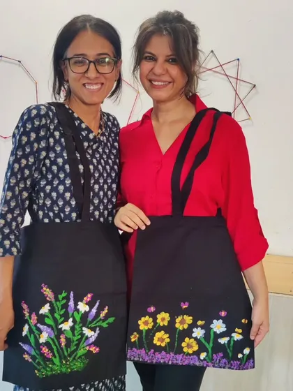 Two of the adult facilitators from the school workshop wearing the floral aprons they painted. This shows that creating art is a joyful activity for all ages.