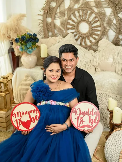 A happy studio maternity portrait with the couple holding signs to announce they are becoming a mom and dad.