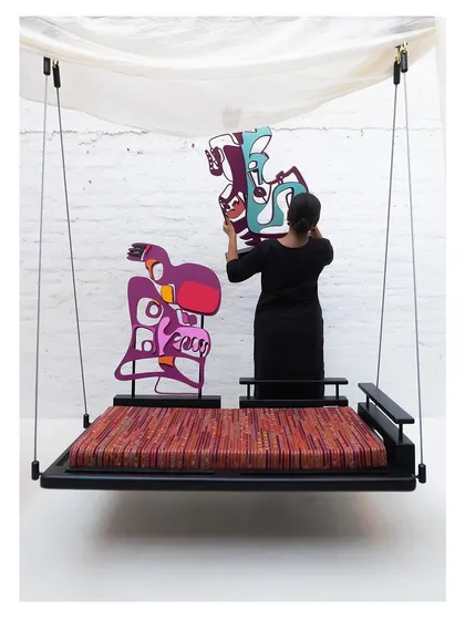 The artist adjusts the placement of a module, highlighting the human-interactive nature of the furniture piece.
