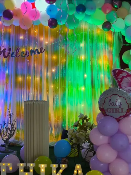 Another view of the baby welcome party, showing the full backdrop with shimmer curtains, balloon pillars, and personalized lighting.