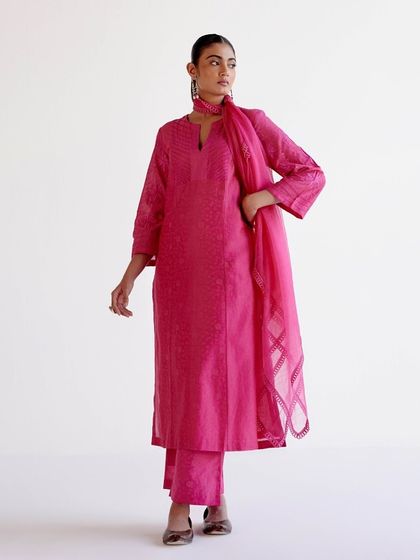 A vibrant fuchsia kurta set with subtle woven patterns and a sheer dupatta, a perfect example of understated elegance.
