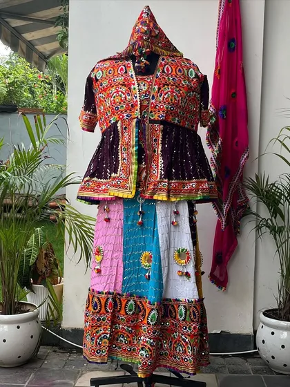 A complete men's outfit on display. This set includes a multi-colored skirt, a heavily embroidered Kedia top, and a matching headpiece (pagdi).
