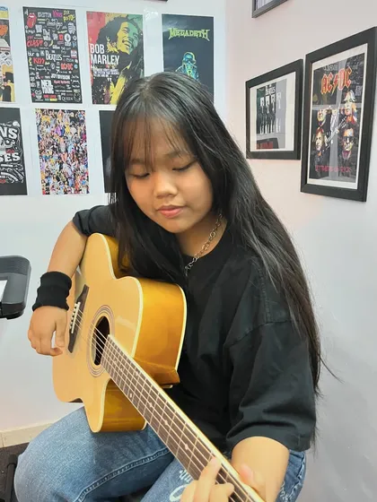 A young student looking confident with her guitar. We aim to build not just skills but also self esteem through music education.