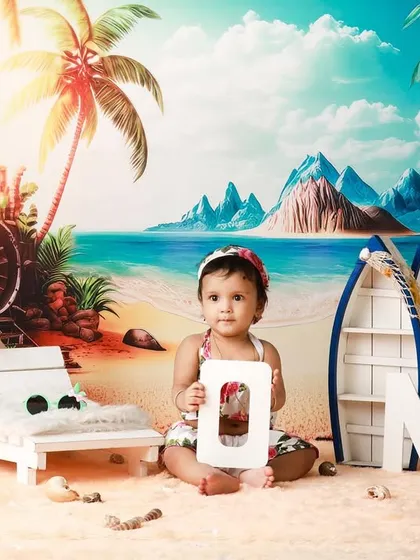 The birthday girl holding the letter 'O' from the 'ONE' sign in our creative beach backdrop.