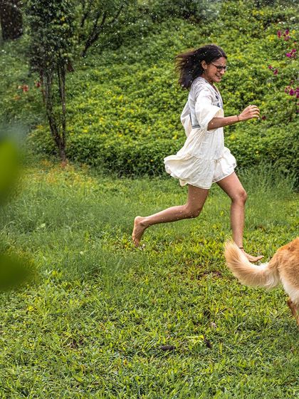 A girl runs barefoot and carefree through the wet grass, her dog just a few steps behind. This image is the essence of freedom and spontaneous joy.