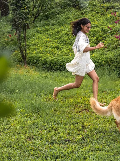 A girl runs barefoot and carefree through the wet grass, her dog just a few steps behind. This image is the essence of freedom and spontaneous joy.