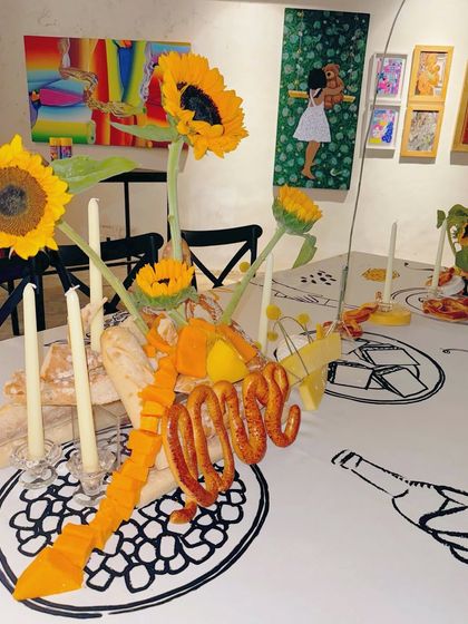 A close-up of the "Love" cheese sculpture, surrounded by fresh sunflowers and baguettes, ready for guests to enjoy.