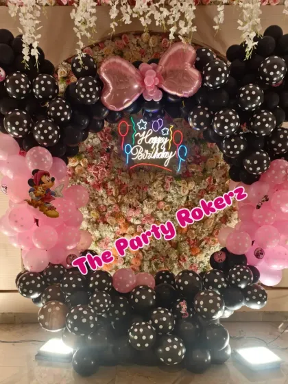 The main photo backdrop for the Minnie Mouse party, featuring a balloon arch with a large pink bow and polka-dotted balloons.