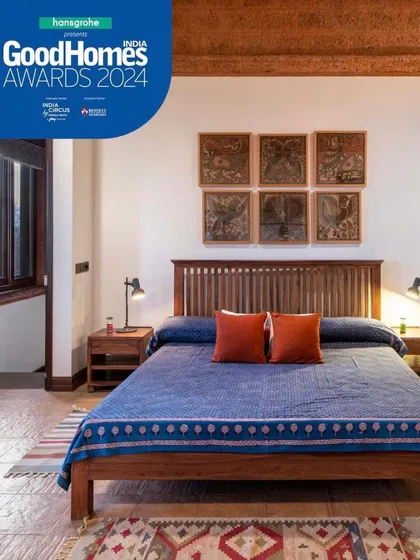 This bedroom is a study in texture and simplicity. The clean lines of the wooden bed are complemented by the earthy tones of the dhurrie and the traditional art on the wall, creating a space that is both modern and timeless.