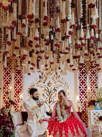 A candid moment between Naomi and Rakshit under a ceiling of hanging rajnigandha and rose garlands. This highlights the intricate floral work that created a fragrant and beautiful canopy for their ceremony.
