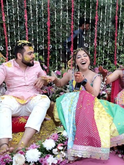 The Haldi ceremony in full swing with color smoke and flying petals. This photo is all about the vibrant, chaotic, and joyful energy that makes this ritual so special.