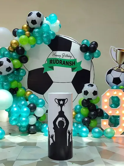 A fantastic football themed birthday party for a 9-year-old. The setup features a giant football backdrop, a balloon arch in team colors, a trophy cutout, and a light-up number '9'.