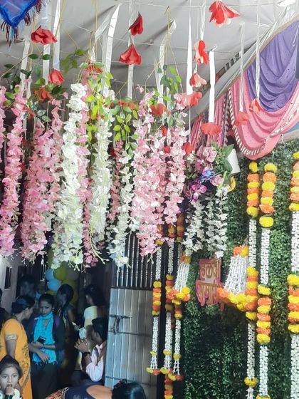 A close-up of the beautiful floral decorations used in a Haldi mandap, featuring hanging wisteria and traditional marigold garlands.
