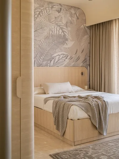 The guest bedroom in our 'Soft Serve' project blends minimalism with organic touches. A botanical mural serves as a backdrop to the custom curved wooden bed, creating the calming ambiance of a boutique bed and breakfast.