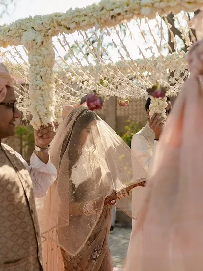 The bride's entry, a classic and emotional moment. The simple yet beautiful floral canopy complements the traditional and graceful aesthetic of the wedding.