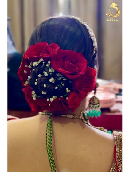 A detailed close-up of the red rose and baby's breath arrangement on a traditional bridal bun.
