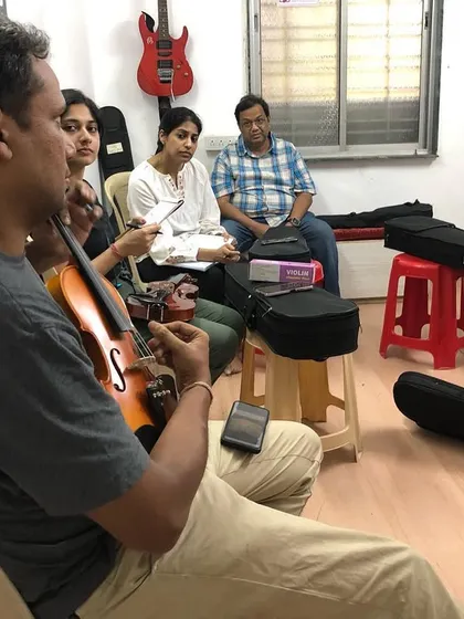 Our violin coach demonstrates a technique to his students. The group setting allows students to learn from the coach and each other in a supportive environment.