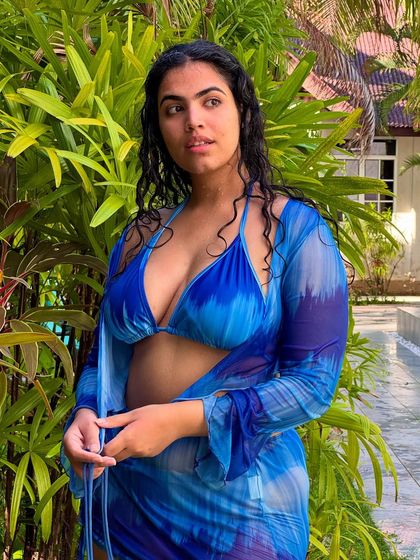 A close-up of the Moana-inspired look, with lush green foliage in the background. The wet hair adds to the 'just came from the ocean' vibe.