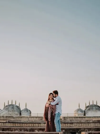 A wide shot of the couple against the unique rooftop architecture of a Jaipur fort, showcasing the expansive views.