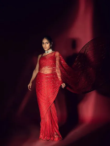 A dramatic, full-length shot where the sleek hairstyle and glowing makeup complement the flowing movement of the red saree.