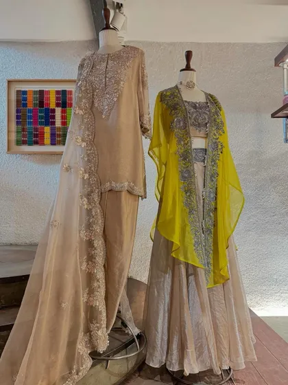 Prisho's breathtakingly detailed outfits. This display features a beige kurta set with a heavy organza dupatta and a lehenga set with a contrasting yellow cape.