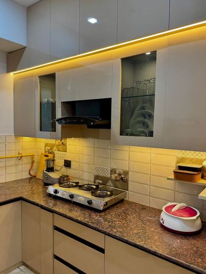 A practical and stylish kitchen setup with beige cabinets, granite countertops, and glass-fronted upper storage.