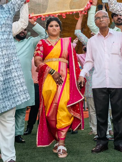 The bride making her grand entry, showcasing the powerful silhouette of the traditional dhoti-style Nauvari saree.
