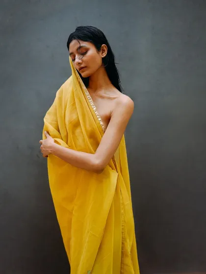 A gentle portrait of a model wrapped in yellow fabric. The soft draping and closed eyes convey a sense of tranquility and grace.